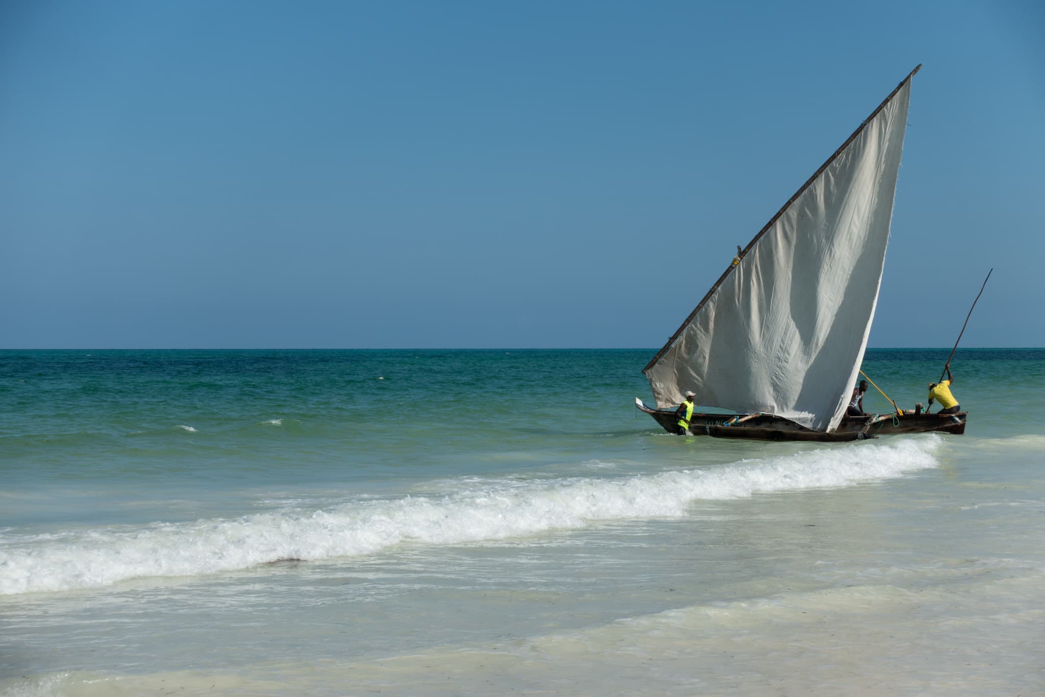 A traditional sailboat crossing turquoise water in Zanzibar